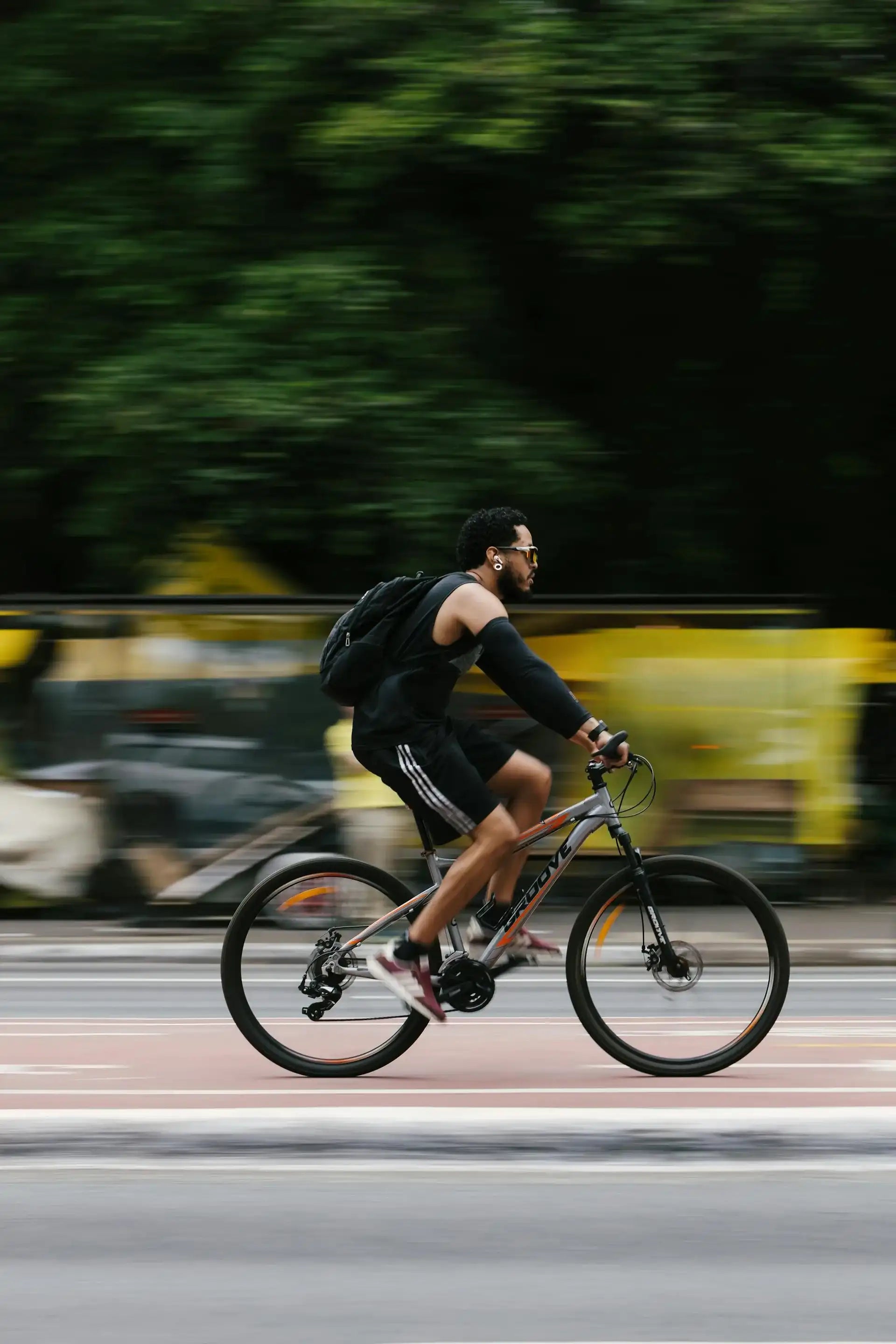 Homme faisant du vélo sur une piste cyclable urbaine avec effet de mouvement.
