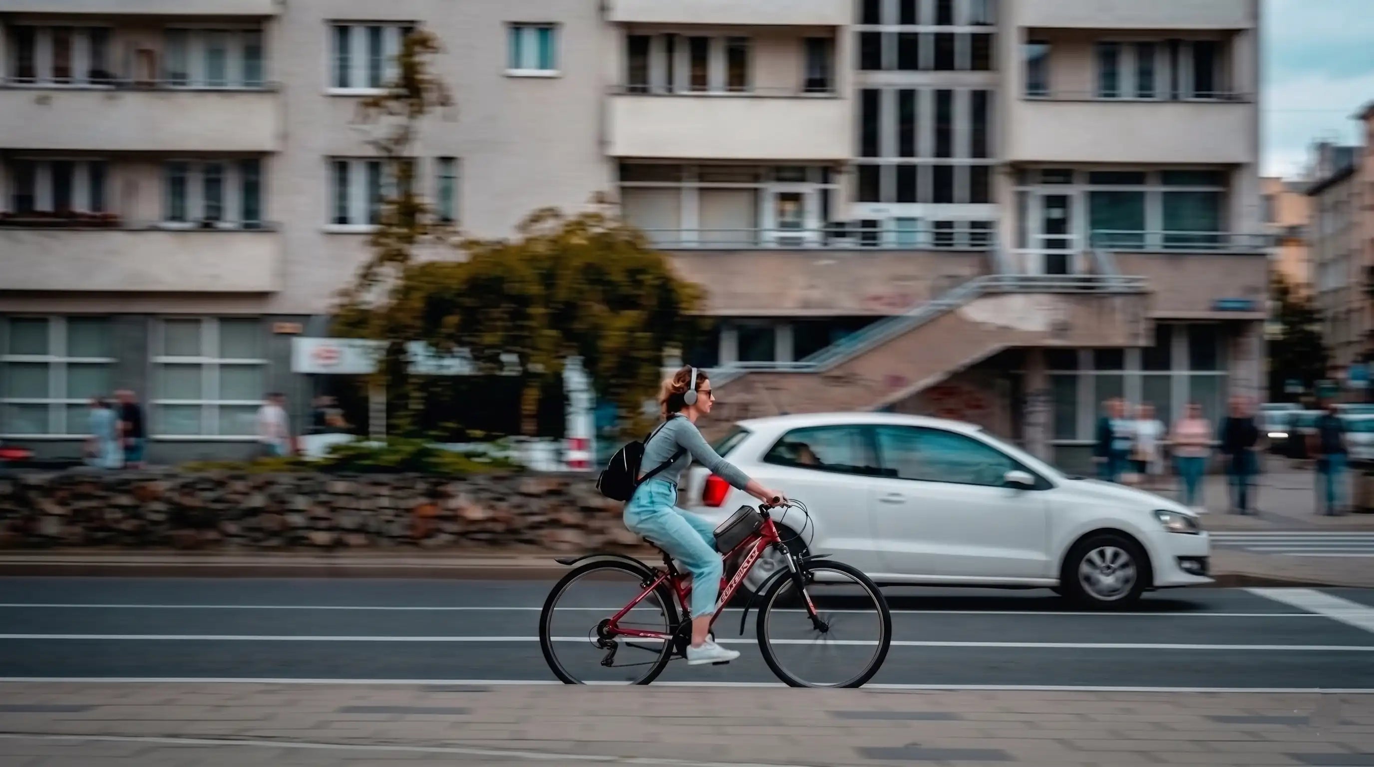 Femme à vélo en ville avec une sacoche de cadre pour smartphone lors d'un trajet urbain.